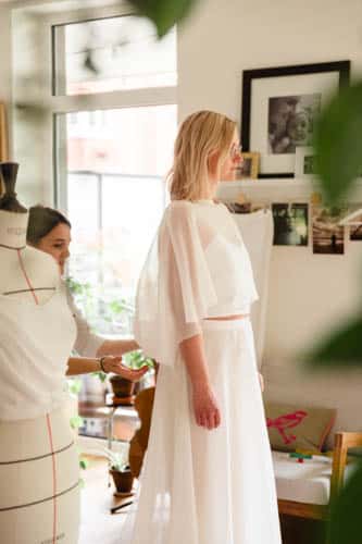 die Massschneiderin prüft die Cape einer Braut für ein urban und elegant Brautkleid