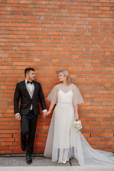 Hochzeitspaar, das sich in Hamburg an den Händen hält - Braut trägt ein schlichtes zweiteiler Brautkleid - Brautatelier Par Amour Hamburg